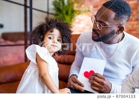 afro american baby giving to dad a Valentine's Day picture in living room 87004133