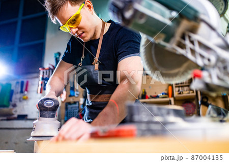 Carpenter young working with wood in workshop 87004135