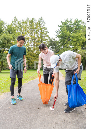 ウオーキングしながら公園を綺麗にする若者たち 87005517