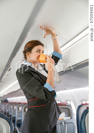 Stewardess demonstrating how to use oxygen mask in aircraft 87009981