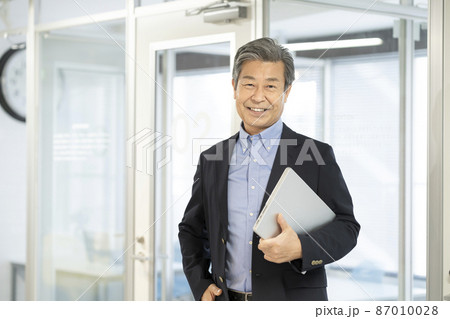 ノートパソコンを持った60代の男性　シニアのビジネスマン 87010028