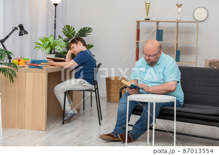 Father and son read books in a common room. Father and son read books in a common room. 87013554