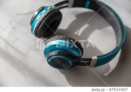 Turquoise and black headphones against a gray background. Wireless device for listening to music and communication. Turquoise and black headphones against a gray background. Wireless device for listening to music and communication. 87014307