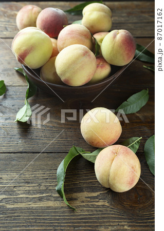 Fresh harvest of peaches in a clay bowl on a wooden rustic table. 87017162