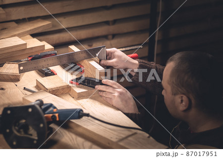 A man makes wood products with the help of special tools. Portrait of a young carpenter at work. Employment in the woodworking industry A man makes wood products with the help of special tools. Portrait of a young carpenter at work. Employment in the woodworking industry 87017951