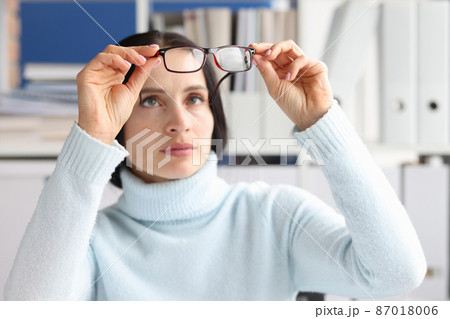 Tired worker with irritated eyes looks at glasses Tired worker with irritated eyes looks at glasses 87018006