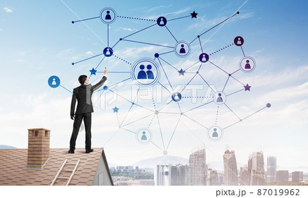 Businessman on house roof presenting networking and connection concept. Mixed media Businessman on house roof presenting networking and connection concept. Mixed media 87019962
