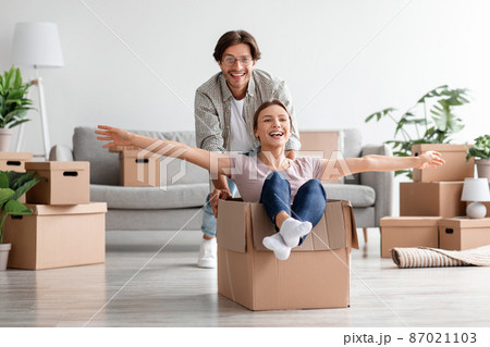 Glad cheerful excited millennial caucasian man in casual and glasses pushes box with woman in room Glad cheerful excited millennial caucasian man in casual and glasses pushes box with woman in room 87021103