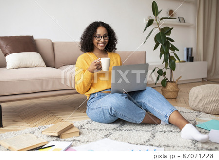 Cheery young black woman having video call with family or friend on laptop, drinking coffee at home, copy space 87021228