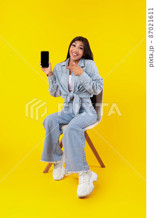 Woman showing white empty smartphone screen and pointing Woman showing white empty smartphone screen and pointing 87021611