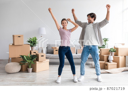 Smiling excited young caucasian family in casual dancing in living room with cardboard boxes, enjoy relocation 87021719