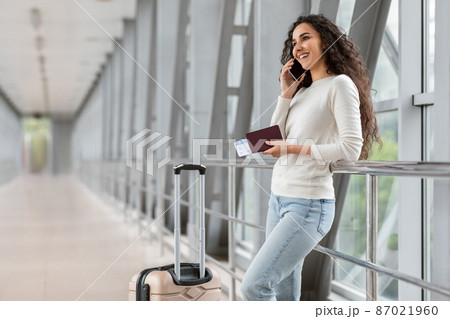 Beautiful Young Brunette Lady Talking On Cellphone While Waiting In Airport Terminal, Beautiful Young Brunette Lady Talking On Cellphone While Waiting In Airport Terminal, 87021960