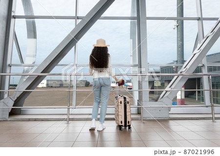 Air Travels. Female Traveller In Wicker Hat Waiting In Airport, Rear View Air Travels. Female Traveller In Wicker Hat Waiting In Airport, Rear View 87021996