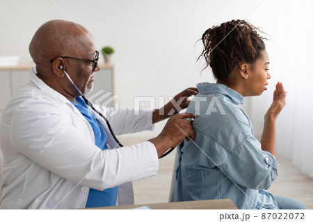Black male doctor checking breath of female patient Black male doctor checking breath of female patient 87022072