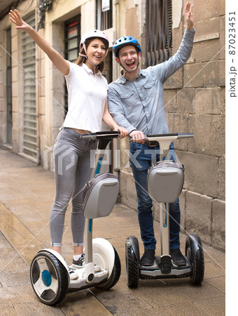 young couple guy and girl walking on segway in streets of european city 87023451