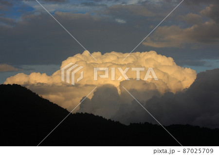 山向こうに現れた赤く染まる積乱雲 87025709