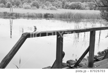 Beautifully standing old wooden bridge over river in colored background 87026703