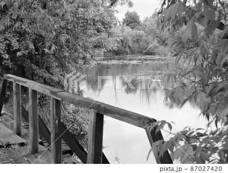 Beautifully standing old wooden bridge over river in colored background 87027420