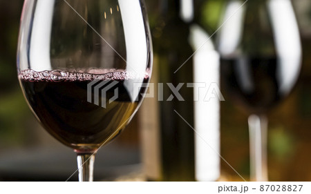 Wine tasting. A glass of red wine on the background of a restaurant table with bottle at an evening dinner or event party. 87028827