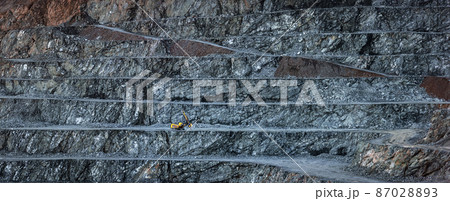Panorama of diabase quarry with stepped wall and one yellow drilling machine 87028893