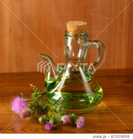 Flowers and oil of thistle on a wooden background. 87029006