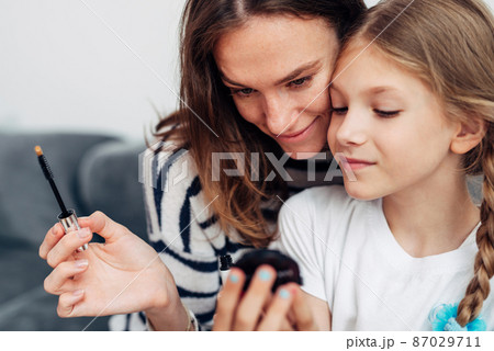 Mother and daughter doing makeup and admiring in a small mirror 87029711