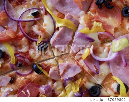 Pizza with ham, tomatoes, sweet peppers and olives, close-up shot. Pizza with ham, tomatoes, sweet peppers and olives, close-up shot. 87029802