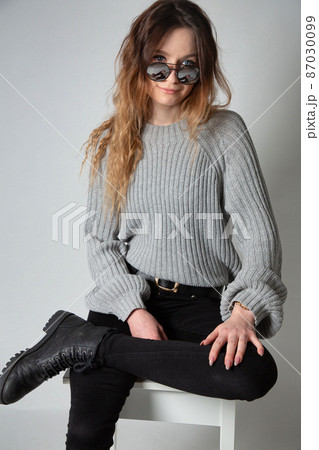 Woman in grey jumper on grey Woman in grey jumper on grey 87030099