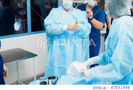 Surgeons dress in sterile blue uniforms before surgery. 87031998
