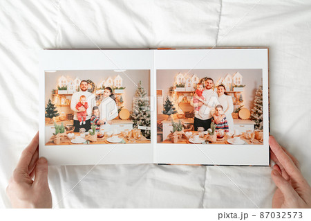a hands with a book with photos of big family on a white background. a hands with a book with photos of big family on a white background. 87032573