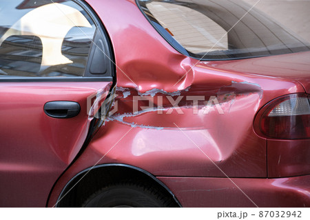 Dented car with damaged body parked on city street side. Road safety and vehicle insurance concept 87032942