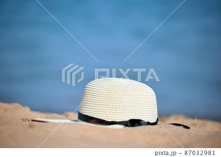 Closeup of yellow straw hat on sandy beach at tropical seaside on warm sunny day. Summer vacation concept. 87032981