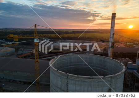 Aerial view of cement factory with high concrete plant structure and tower crane at industrial production area. Manufacture and global industry concept. Aerial view of cement factory with high concrete plant structure and tower crane at industrial production area. Manufacture and global industry concept. 87033762