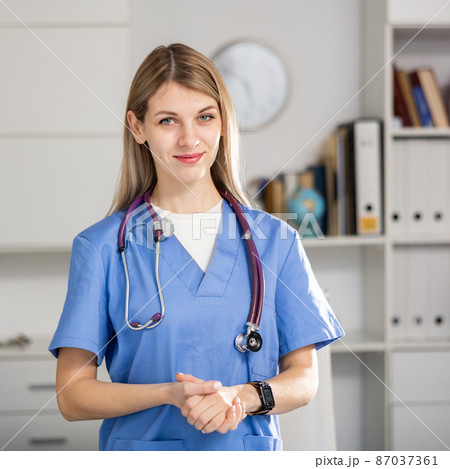 nurse standing in medical office with clipboard 87037361