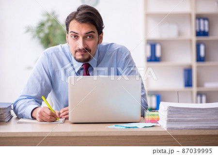 Young male employee and too much work in the office 87039995