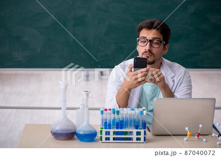 Young male chemist in front of blackboard 87040072
