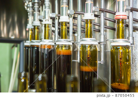 Unlabeled glass bottles in bottling machine at modern winery 87050455
