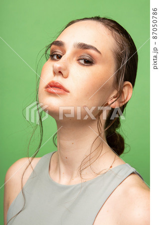 Young woman with dark gathered hair on green 87050786
