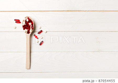 Vitamin capsules in a wooden spoon on a colored background. Pills served as a healthy meal. Drugs, pharmacy, medicine or medical healthycare concept Vitamin capsules in a wooden spoon on a colored background. Pills served as a healthy meal. Drugs, pharmacy, medicine or medical healthycare concept 87054455