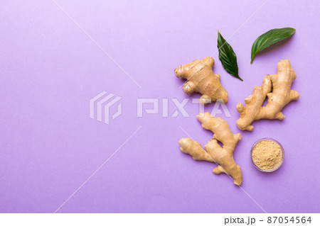 Finely dry Ginger powder in bowl with green leaves isolated on colored background. top view flat lay 87054564