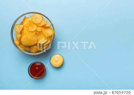 Top view chips with sause in bowl on colored background, top view with copy space Top view chips with sause in bowl on colored background, top view with copy space 87054720