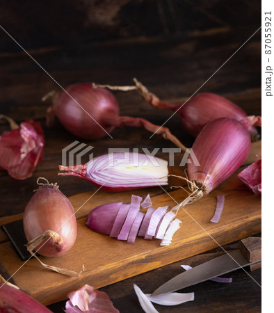 Sliced Red tropea onions with a knife on a wooden board close up Sliced Red tropea onions with a knife on a wooden board close up 87055921