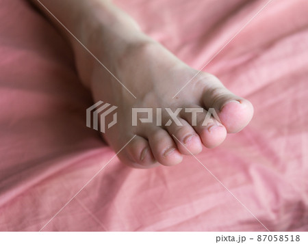 Female toes on a pink bed sheet in apartment 87058518