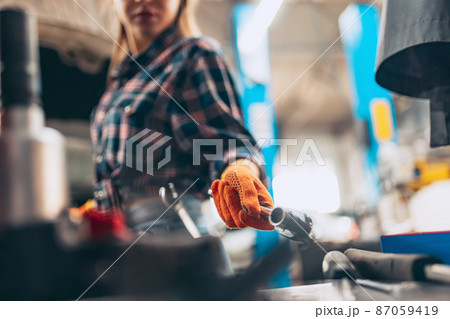Female auto mechanic. beautiful young red-headed girl in working process at auto service station, indoors. Gender equality. Work, occupation, fashion, job Female auto mechanic. beautiful young red-headed girl in working process at auto service station, indoors. Gender equality. Work, occupation, fashion, job 87059419