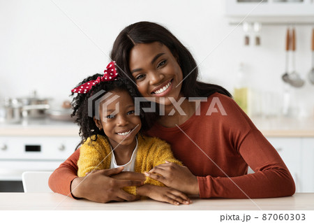 Happy Beautiful Black Mother And Her Little Daughter Posing In Kitchen Interior Happy Beautiful Black Mother And Her Little Daughter Posing In Kitchen Interior 87060303