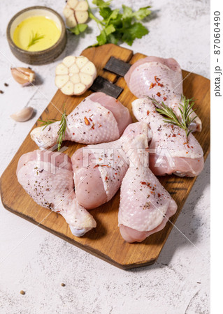 Chicken meat. Raw fresh chicken drumsticks with spices on a woden cutting board on a stone countertop. Chicken meat. Raw fresh chicken drumsticks with spices on a woden cutting board on a stone countertop. 87060490