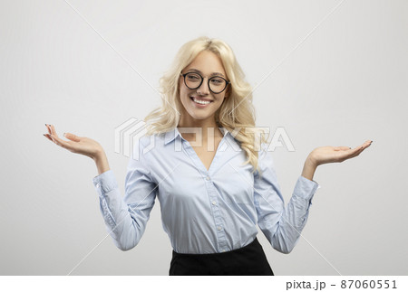 Positive woman in formal wear comparing options, making scales with her hands, holding invisible objects Positive woman in formal wear comparing options, making scales with her hands, holding invisible objects 87060551