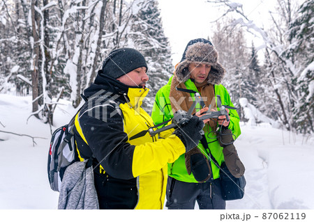 two men in the winter forest launch a quadcopter 87062119