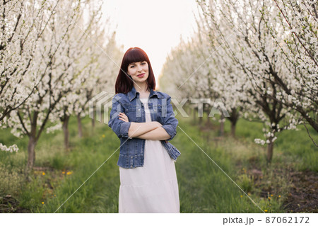 Stunning woman with crossed arms posing at blooming orchard Stunning woman with crossed arms posing at blooming orchard 87062172