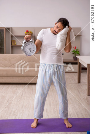 Young man doing sport exercises at home in time management conce 87062291